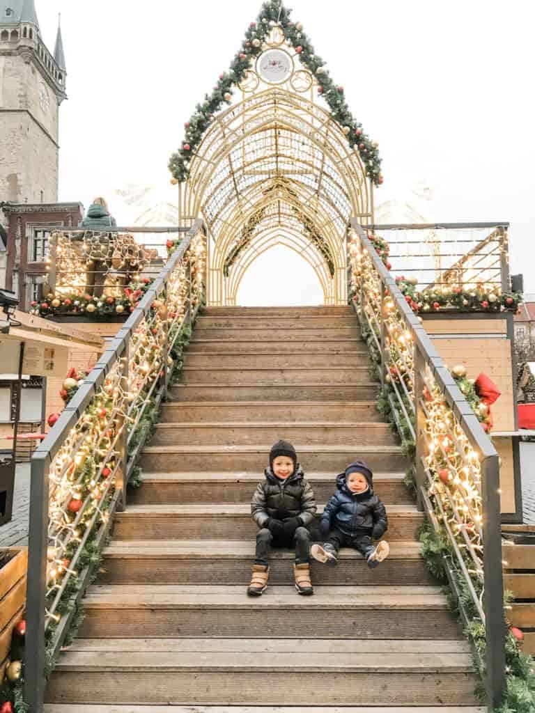 Boys sitting on stairs at Prague Christmas market during a European Christmas market itinerary
