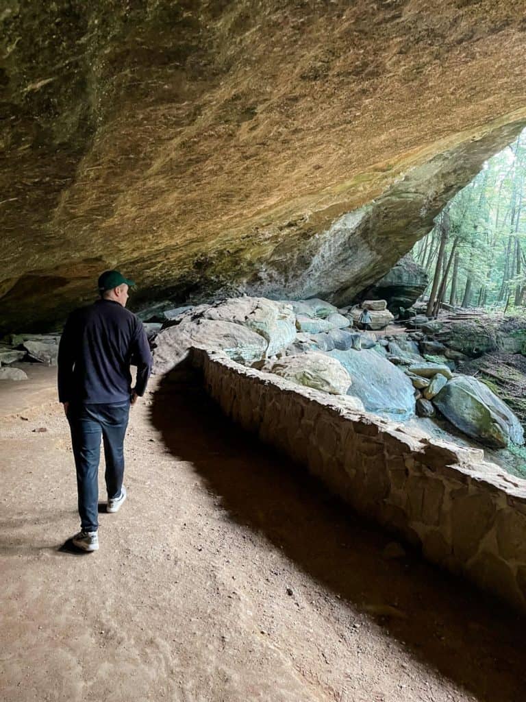 Man walking with Old Man's Cave towering overhead