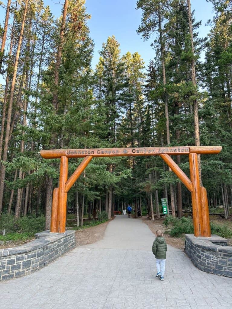 Boy walking under arch to Johnston Canyon trail in Banff National Park