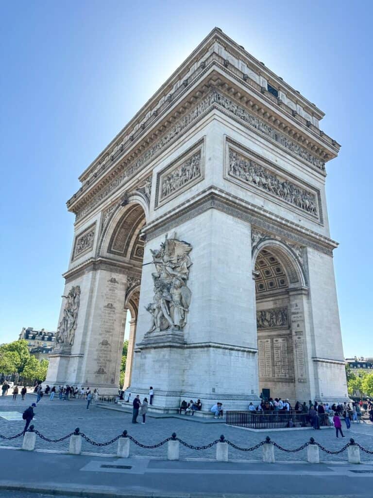 Majestic Arc de Triomphe monument in Paris with intricate sculptures and details, driving past on hop-on-hop-off bus